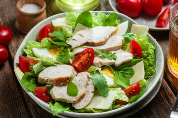 Salad of chicken fillet, eggs, tomatoes and cheese in a plate. Caesar salad