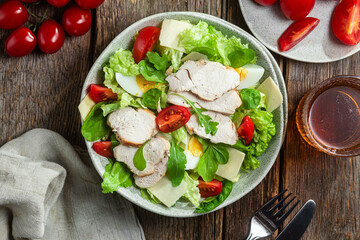 Salad of chicken fillet, eggs, tomatoes and cheese in a plate. Caesar salad