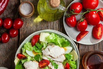 Salad of chicken fillet, eggs, tomatoes and cheese in a plate. Caesar salad