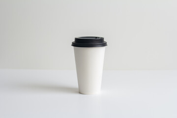 a white paper coffee cup with a lid without inscriptions stands on the table