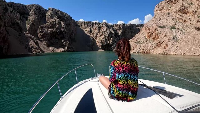 A woman looks out over a river canyon from the deck of fast boat.