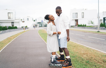 Happy African American couple in roller blades hugging on street