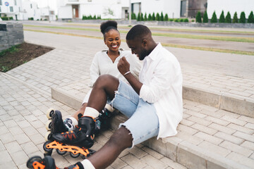 Smiling black couple sitting on stairs of pavement and laughing together