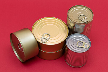 A Group of Stacked Tin Cans with Blank Edges on Red Background. Canned Food. Different Aluminum Cans for Safe and Long Term Storage of Food. Steel Sealed Food Storage Containers