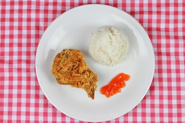 Crispy fried chicken served with rice and chilli sauce on a white plate