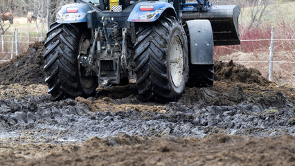 A tractor moving horse manure in a field