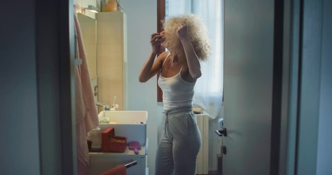 Young Brazilian Woman in Apartment Bathroom Singing and Dancing While Styling her Hair. Beautiful Carefree Female with Curly Hair Enjoying her Time in the Morning, Getting Ready for Work. Slow Motion