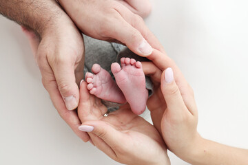 The palms of the father, the mother are holding the foot of the newborn baby on white background....