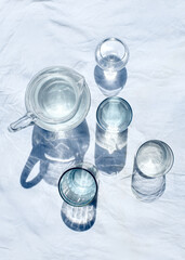 glasses and a carafe filled with water stand on a white tablecloth