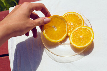 a woman's hand holds a piece of sliced, juicy orange