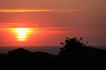 at the sea the red-golden sun shines out from behind the clouds before it sets