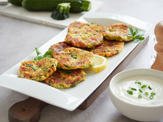 Vegetable fritters. Vegetarian zucchini and carrot pancakes served with cream sauce, lemon and...