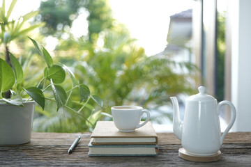 white tea cup and tea pot and plant pot and notebook on wooden tray and table balcony outdoor view