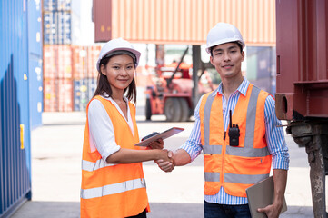Asian dock control man and woman logistics worker wear safety helmets and protect suite working in shipping container, commercial transport background. - 615823052