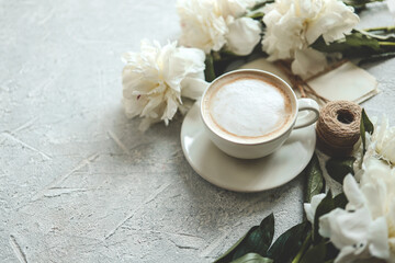 Summer composition top view. Cup of coffee, peonies and vintage letters on gray background