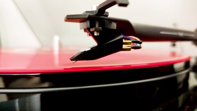 Retro Turntable System Playing a Red Vinyl Record. Close up View of the Stylus Needle on the Vintage Spinning Vinyl LP. 4K Video Footage.