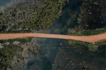 drone view of a dirt road and lake 