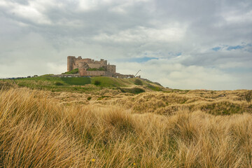 Zamek Bamburgh (ang. Bamburgh Castle) – zamek nad brzegiem Morza Północnego w miejscowości Bamburgh, zdjęcie od strony wydm morskich. 