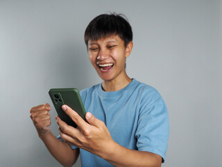 Asian man looks at smartphone, happy, excited