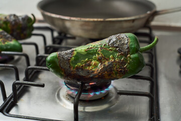 Poblano peppers roasted on the stove. Mexican cooking technique also called tatemar or tatemados.
