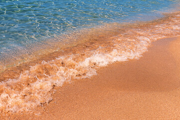 Soft sea wave on a sandy beach. Calm soft waves roll foam on the golden sandy beach