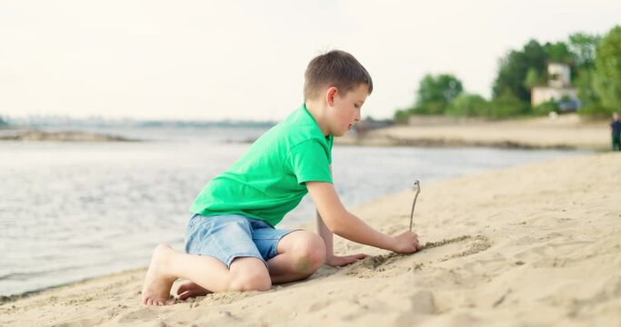 Child boy playing with sand on sea beach in warm sunshine in the summer