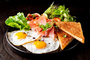 fried eggs with ham, salad and hummus