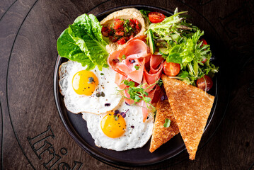 fried eggs with ham, salad and hummus