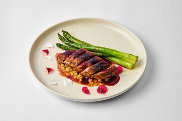 Baked duck breast with cherry sauce and asparagus in a plate