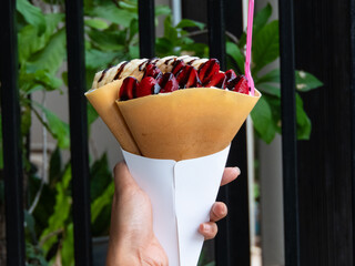 Crispy crepe filled with luscious strawberry whipped cream is a delightful treat that combines the satisfying crunch of the crepe with the light and creamy sweetness of the strawberry filling.close up