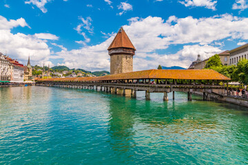 Fototapeta na wymiar Picturesque view of Lucerne's landmark and symbol, the famous covered timber footbridge Kapellbrücke (Chapel Bridge) with the Water Tower, over the river Reuss with its turquoise water.