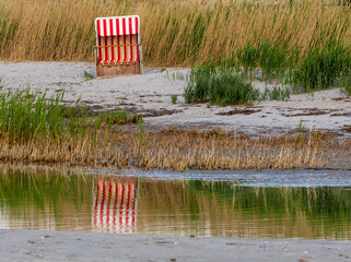 Roter Strandkorb Spieglung im Wasser am Strand 