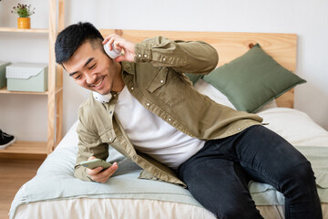 Fototapeta premium Man lying in bed watching videos on his cell phone.