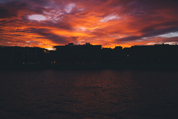 Bright sunset sky over silhouette of city and sea