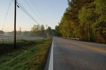 Sunrise by a road on a foggy morning