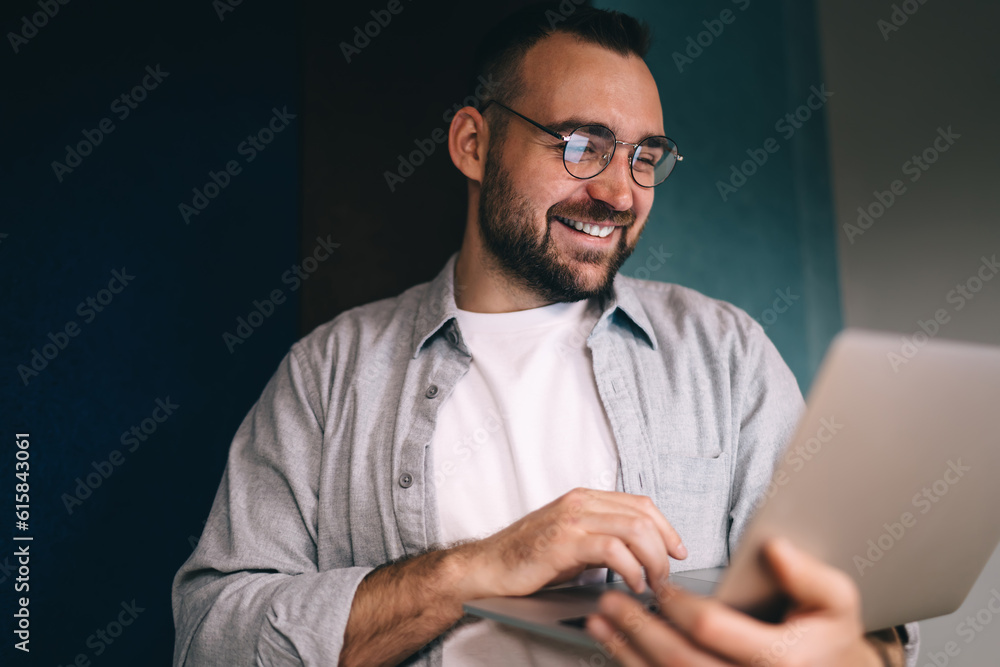 Aufkleber smiling man in casual outfit and glasses using netbook