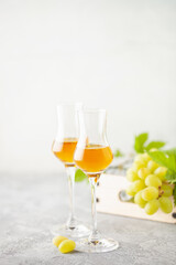 Gold grappa in grappas wineglasses and fresh grapes on the gray background. Alcohol concept