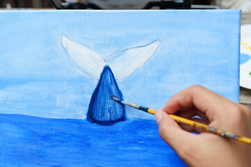 Painter's hand is holding brush to paint a beautiful dolphin painting. Learn to paint in your free time. paint on white cloth with the intention of creating beautiful images as intended by art school © Ekkasit A Siam