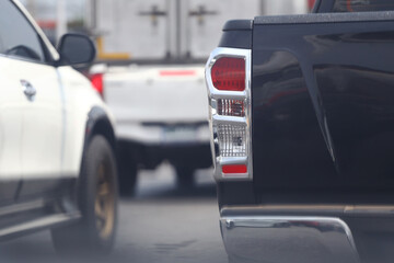 The taillight of a braking car on the road and a blurred image behind another car.