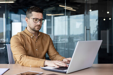 Portrait of a serious young male programmer, specialist developer who is concentrating on working...