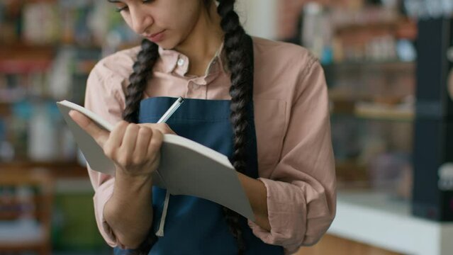 Indian arabian female staff waitress writing in notebook taking customer order in cafe woman catering employee worker take reservation serving restaurant client in cafeteria catering service concept