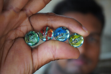 Four different colored marbles are arranged side by side between two fingers