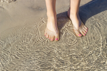 walks on the beach, feet in the water on a sandy beach in clear water