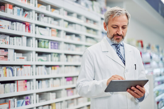 A serious male pharmacist using a digital tablet for work in the pharmacy.