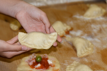 Female hands holding an apulian pie called panzerotti, made with tomato sauce, mozzarella and...
