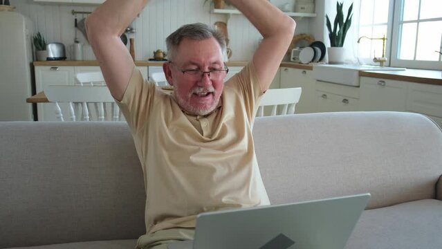 Excited middle aged senior man euphoric winner. Older mature grandfather looking at laptop reading great news getting good result winning online bid feeling amazed. Winning gesture
