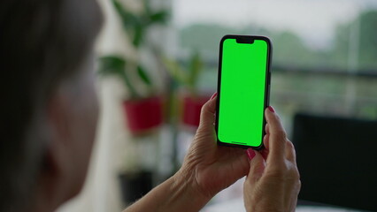 Senior person hands holding smartphone with Chroma key greenscreen. Older person looking at phone screen