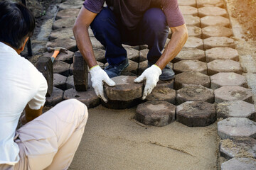 Hands of workman make it fit and to place stone pavers in a row. Construction site of pavement...