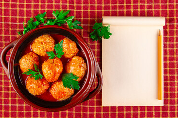 Blank recipebook and kottbullar meatballs in red sauce.
