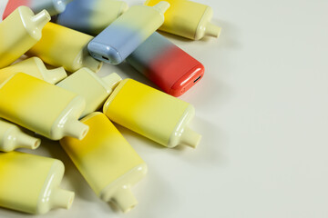 A set of multi-colored disposable electronic cigarettes on a light background close-up. The concept of modern smoking, vaping and nicotine